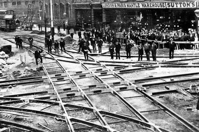 The junction of Briggate and Boar Lane during the relaying of tram tracks in September 1899. The tracks were made at Hunslet Steel Works and laid out in a network. The spaces were filled with end grain wood blocks in this particular area instead of the usual stone setts in an effort to reduce noise. In the background is the spire of the Holy Trinity Church.