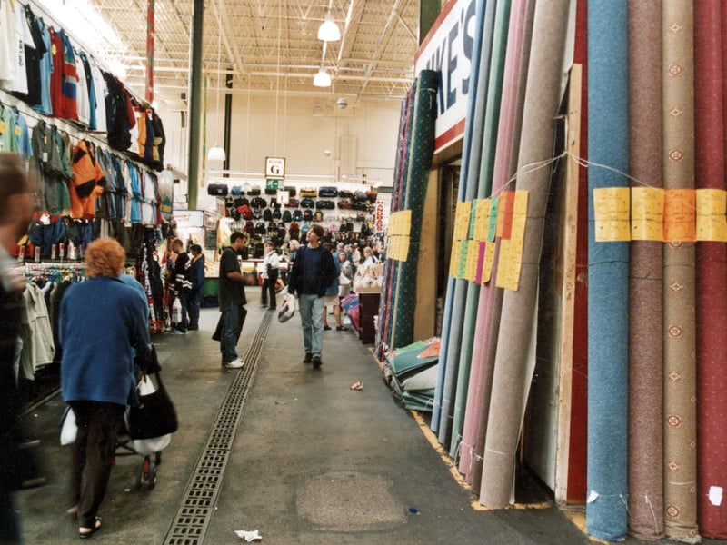 Inside the market from September 1999 showing Mike's carpet stall on the right and a clothes stall on the left. Across rows G and F can be seen a bag and suitcase stall.