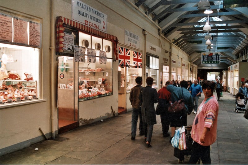 A view along Butcher's Row in the indoor section of the Market in September 1999. The area is full of shoppers and a "fish market" sign is overhead. 
