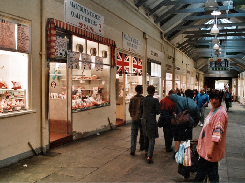 A view along Butcher's Row in the indoor section of the Market in September 1999. The area is full of shoppers and a "fish market" sign is overhead. 