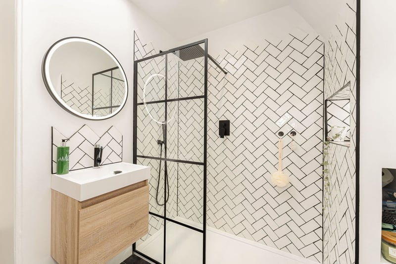 The stylish upstairs shower room with handmade tiles, recessed and lit shower shelf, and black matt hardware that includes a waterfall shower and separate attachment.