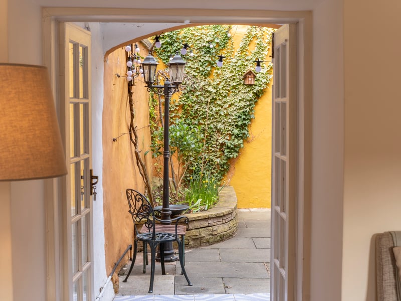 Exterior: French doors in the lounge open to a courtyard garden with raised flower beds and a water feature.