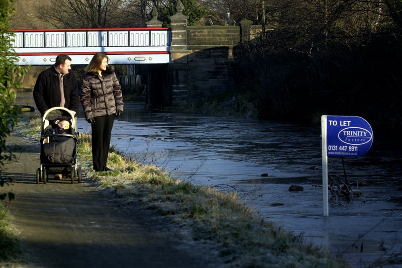 A couple and their baby look at a 'to let' sign which was frozen upright in the Union Canal in January. 2003.