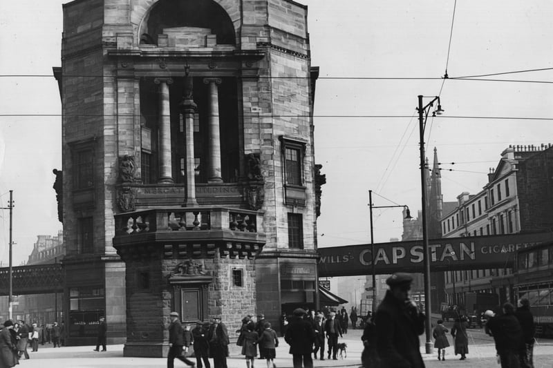The Mercat Cross in Glasgow. The cross is a 1929 replica of the medieval original and the arch behind is all that remains of St Mary's Church after it was burnt down by the local Hell Fire Club with it being pictured here in April 1935.
