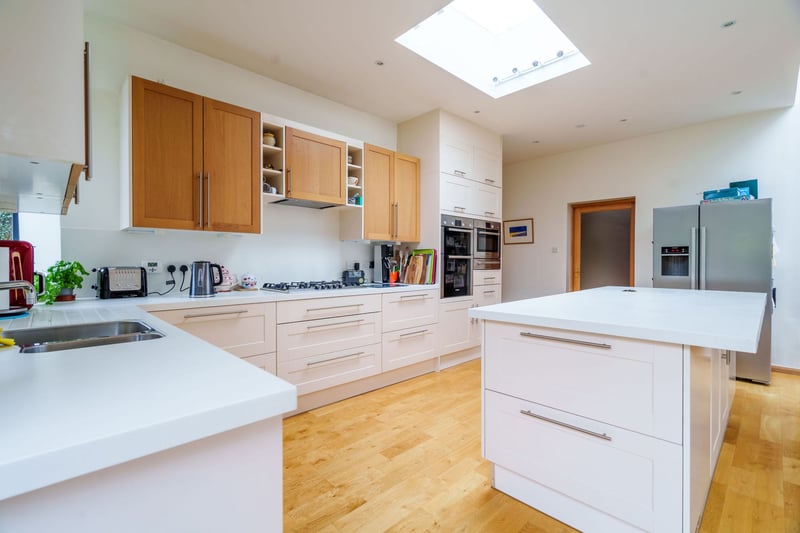 The open plan kitchen has an impressive island with hidden sockets, and is fitted with quality integrated appliances that include BOSCH oven, grill, warming drawer, microwave, five ring hob and dishwasher. 