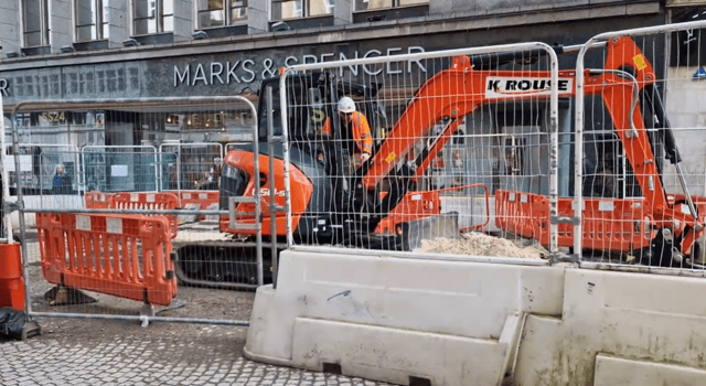 Contractor operating a mini-digger outside Marks & Spencer on Fargate.
