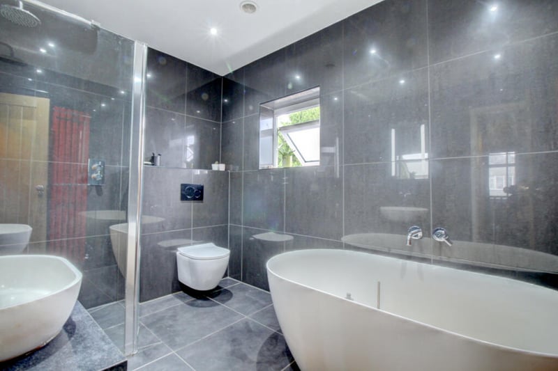 The fully tiled house bathroom features a free-standing bath and large shower.
