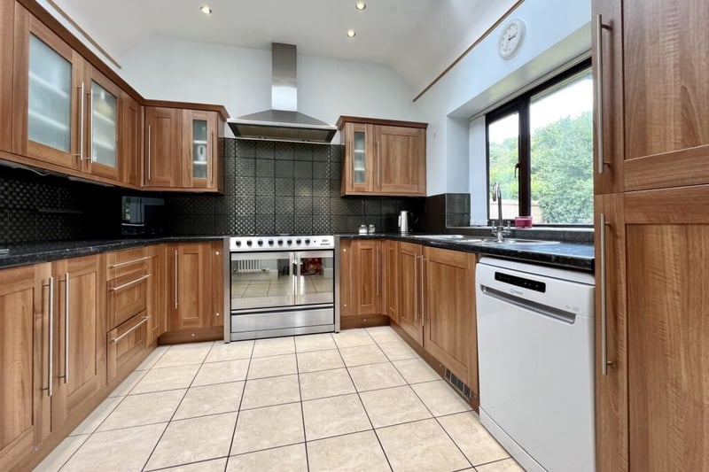 A well-equipped fitted kitchen with base and high level wood effect units overlooking decked patio area.
