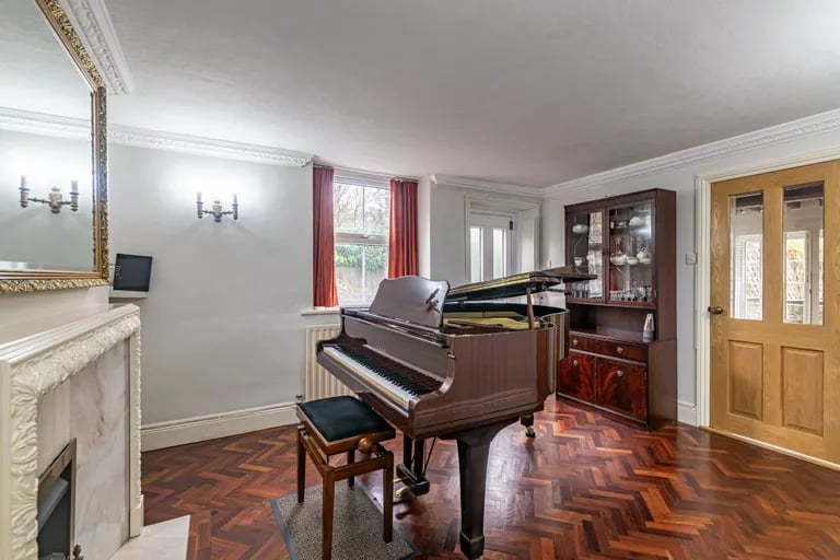 The stylish piano room features stunning parquet floors and feature fireplace.