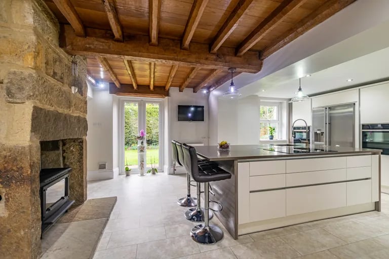 The kitchen features a range of Linda Barker kitchen units and large central island combined with an exposed stone chimney breast and stylish wooden ceiling.