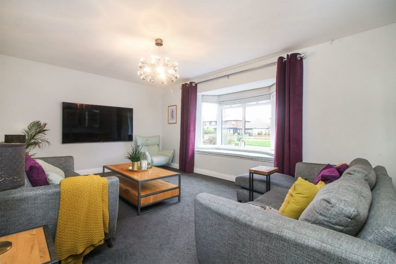 The property's living room is spacious, welcoming and well lit with a big bay window.