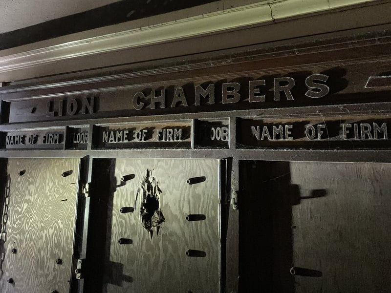 The old directory board of the building, among the original features that remain within the boarded up structure.