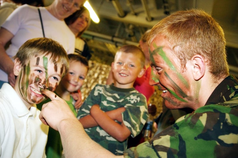 Nine year old Michael Watkis has his face covered in camouflage paint by Marine Arran Faramus during a 2004 open day.
