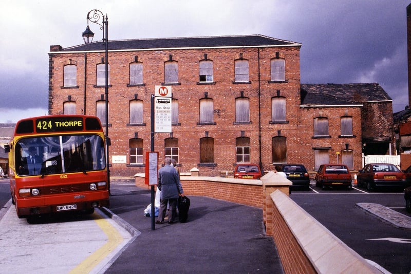 Commercial Street Mills (formerly Greenwood and Walsh's, fronting Ackroyd Street.) This was after the building had become subject to a preservation order, but before work commenced in converting the mill into flats. Windows on all floors here are boarded up. The Black Prince bus, on service no. 424 to Thorpe, is parked on a new lay-by. Pictured in October 1995.