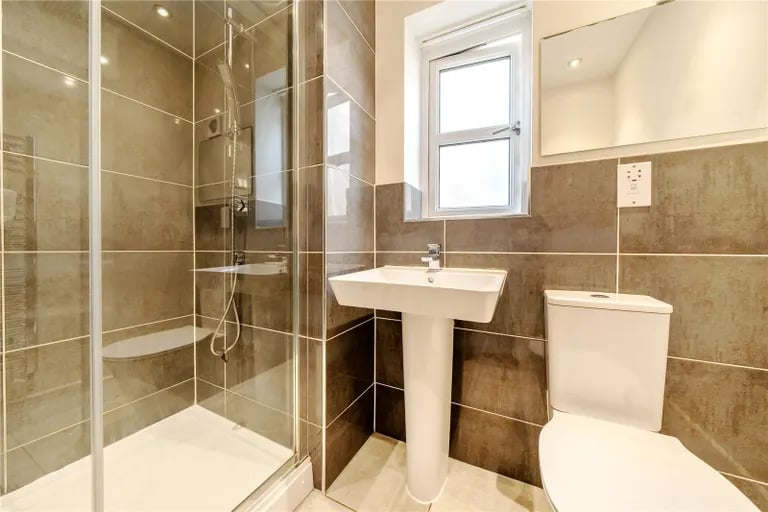 The modern en-suite has a large walk-in shower, wash hand basin and WC.