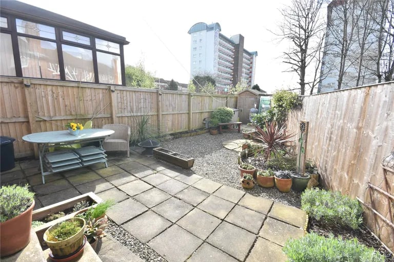 The enclosed space also features a flagged patio seating area and a wood-built garden shed.