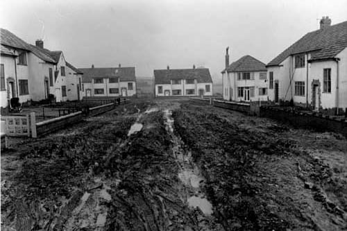 Nos. 43 to 47 Gainsborough Avenue in February 1954. This view looks north towards the junction with Kingsley Drive. The roads are unmade and muddy. A pram is outside a semi-detached house on the left.