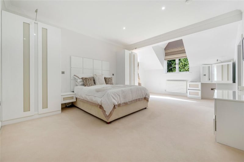 The main bedroom features fitted bespoke wardrobes, a dressing table and a walk-in wardrobe.