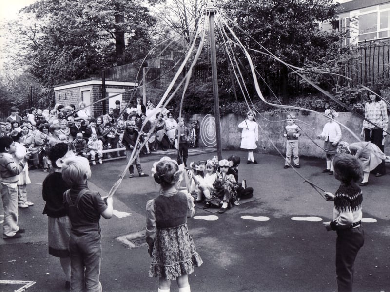 Children of Hucklow First School, in Firth Park, Sheffield, dance round the maypole before an audience of parents in the schoolyard in May 1983