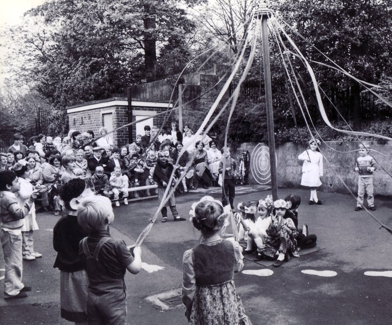 Children of Hucklow First School, in Firth Park, Sheffield, dance round the maypole before an audience of parents in the schoolyard in May 1983