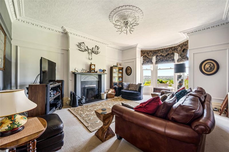 An elegant sitting room with fireplace and large bay window providing breathtaking views.