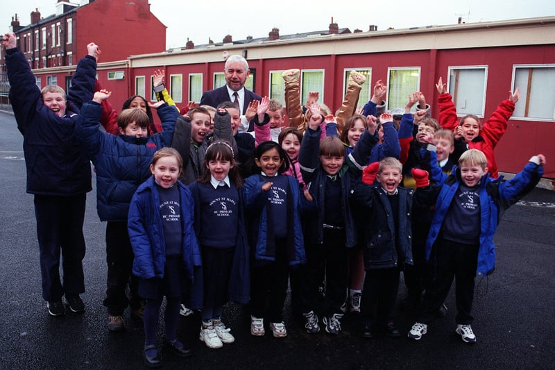 Headteacher Martin Flannery with Year 1,2 and 4 pupils in the playground in front of the old building in December 1999. They had  been awarded £40,000 for a rebuild and were studying in a temporary building while the work was carried out.