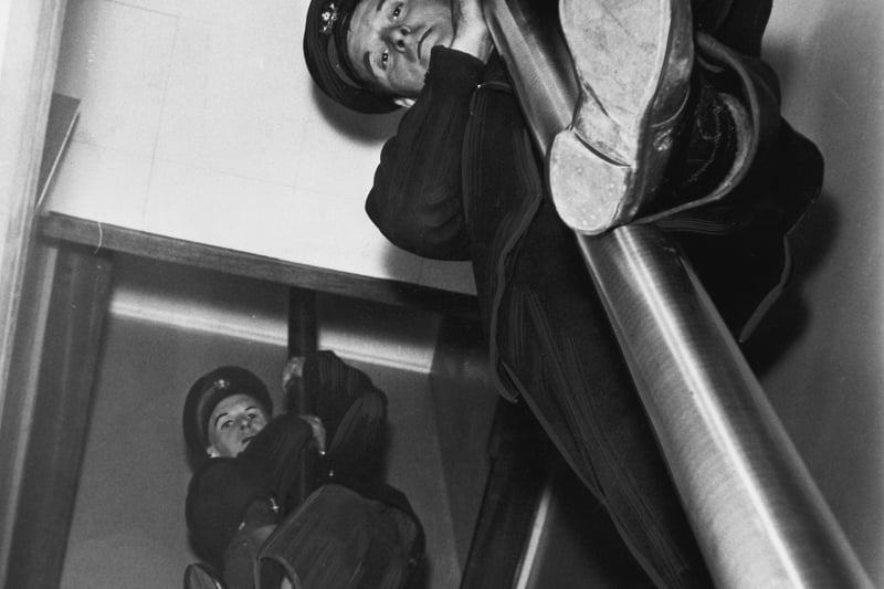 A test run at the new fire station at Harrogate in December 1966. Firefighter George Hardcastle prepares to slide down the other pole to the ground floor.