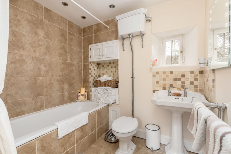 The modern family bathroom (refitted 2008) with small window to front, cosy underfloor heating, a bath with mains shower over, period style sink, high level cistern wc, period style heated towel rail and some built-in storage.