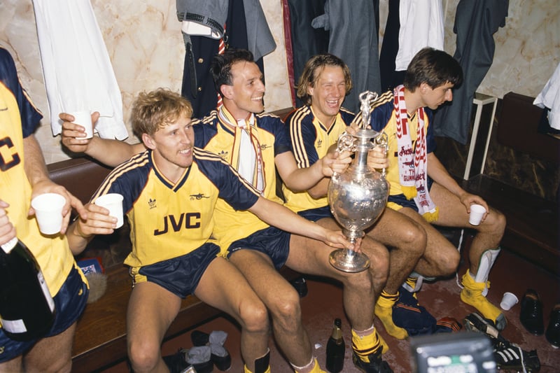 Arsenal players (l-r) Kevin Richardson, Steve Bould, Paul Merson and Alan Smith celebrate in the Anfield dressing room with the League Division One trophy on May 26 1989 after Arsenal had beaten Liverpool 2-0 in the final game of the season to pip them to the title. 