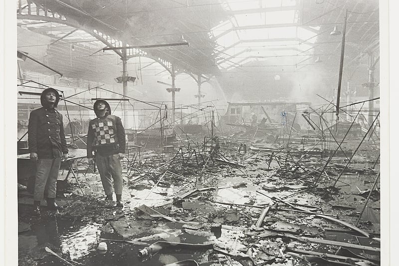 A fire ripped through the main Queen's Hall of the exhibition centre, destroying large portions of the Midlands Caravan, Camping and Leisure Exhibition which had only opened a day earlier on April 15, 1984. The King's and Princess Halls are mentioned. The photograph shows firemen in the gutted hall surrounded by debris.