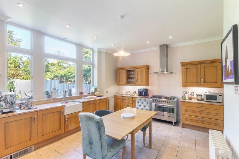 The property's kitchen features a range of cabinetry, tiled flooring, a Belfast sink and a free standing range cooker.