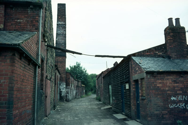Derelict buildings of Woodlands Dyeworks on Wood Lane, including a tall chimney, taken shortly before their demolition. Also known as Crowther's Mill, the dyeworks had been the business of the Crowther family since Edward Crowther took over the site in 1906, though the mill itself is believed to have dated back to about 1601. Pictured in July 1975.