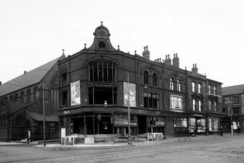 The north west side of Burmantofts Street pictured in December 1945. Numbers 1 to 3 are derelict, number 5 is 'Midland Bank', number 7 is 'W.P.Walker, tobacconists' and number 9 belongs to 'A. Runton & Co. Ltd, boot repairs'. Just visible to the right of the photograph is number 11 'S. Mathers, house furnisher'. To the left of the picture is a church.