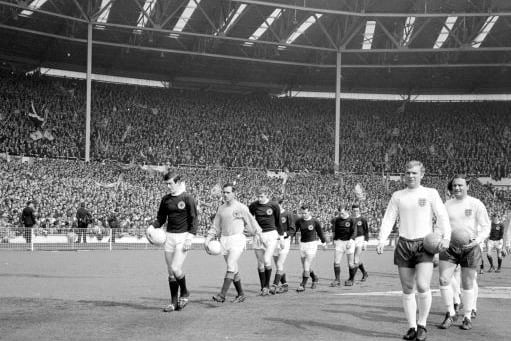 Scotland captain John Greig walks his Scotland team out of Wembley alongside Three Lions skipper Bobby Moore.