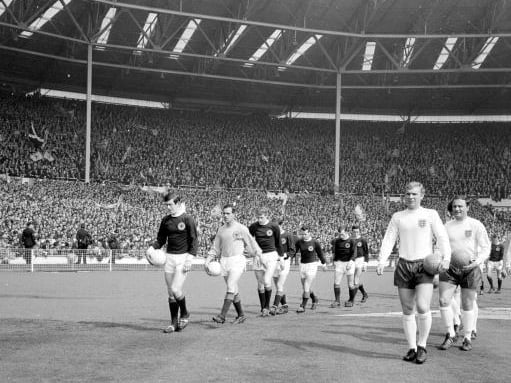 Scotland captain John Greig walks his Scotland team out of Wembley alongside Three Lions skipper Bobby Moore.