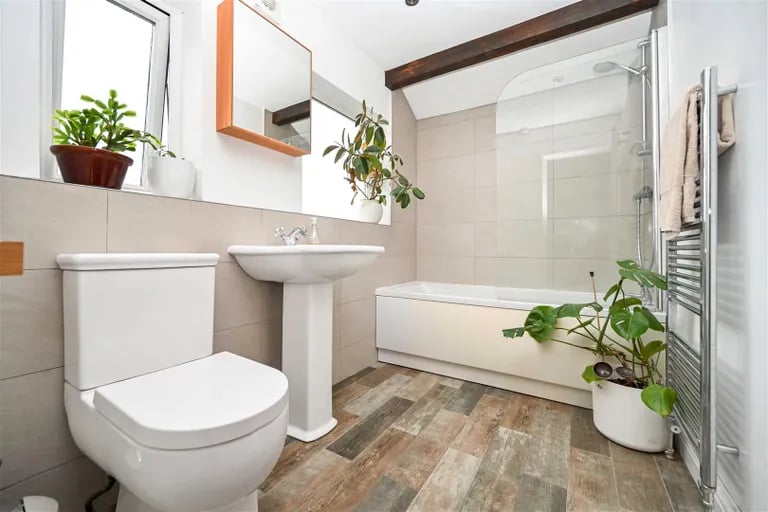 The house bathroom is a stylish suite with shower over bathtub.
