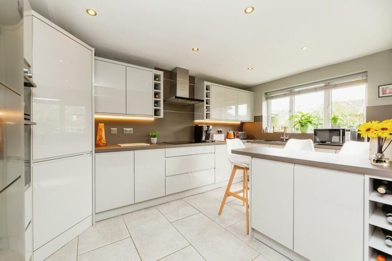Recently refurbished, this stunning, light and airy breakfast kitchen is really the heart of the home, hosting an array of light grey gloss wall and base units providing plenty of storage space, contrasting dark grey worktops, matching breakfast bar, inset black sink and drainer with chrome mixer tap, inset Bosch induction hob with Neff stainless steel cooker hood above, integrated stainless steel Bosch double oven, space for an American style fridge, integrated dishwasher, integrated washing machine, inset spotlights, porcelain floor tiling with luxurious underfloor heating, tall modern grey radiator and large uPVC window overlooking the garden.