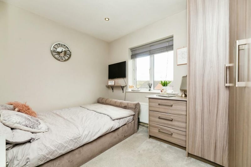 A further double bedroom hosting light grey/brown wardrobes, wall mounted radiator and rear facing uPVC window.