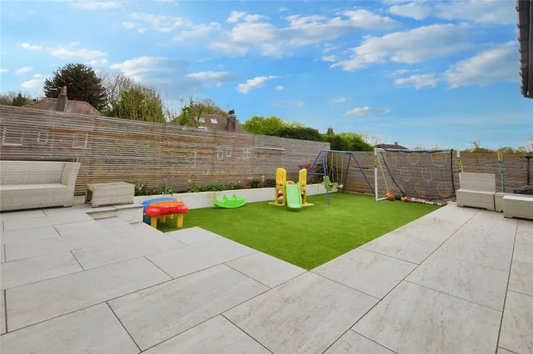 It includes a large porcelain patio space with rendered retaining walls.