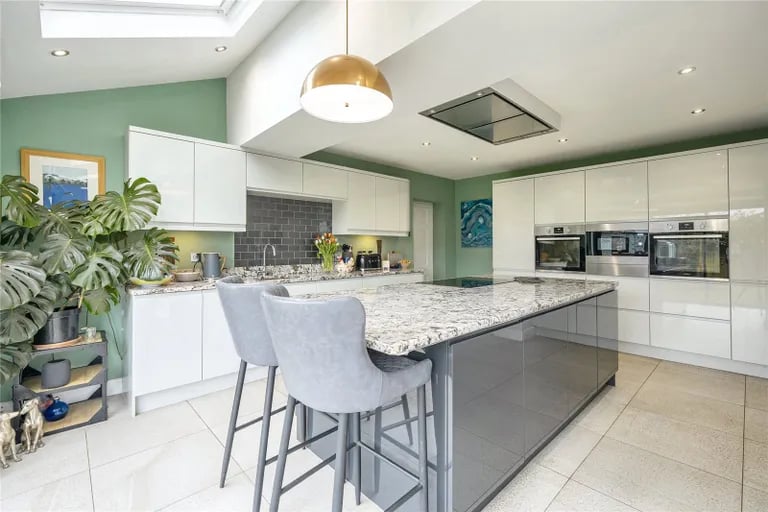The kitchen is fitted with an extensive range of units, with a large central island and integrated appliances.