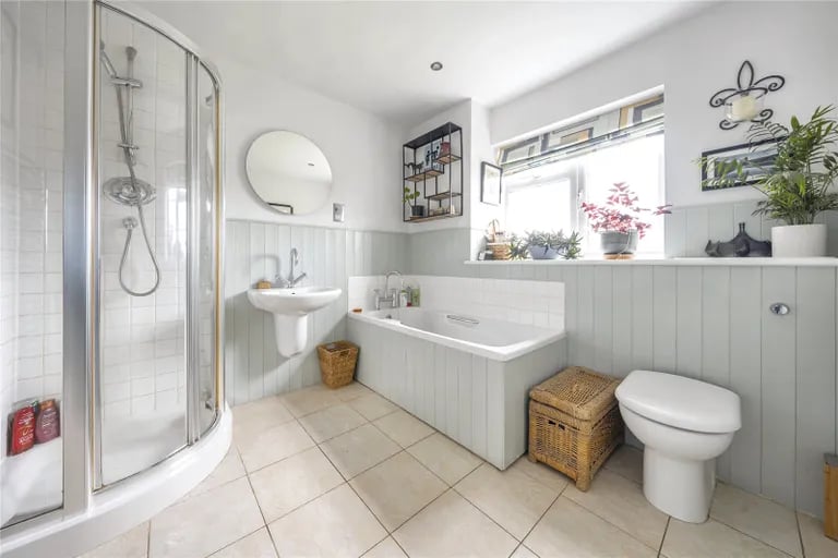 The stylish family bathroom has a bathtub and large shower cubicle.