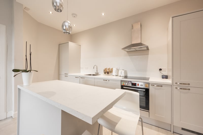 The fully-fitted kitchen, complete with a striking feature island, perfect for social gatherings. Equipped with an integrated washing machine and fridge freezer, the kitchen offers ample space for versatile configurations. 