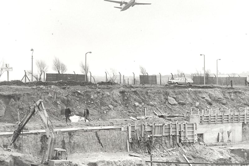 Aircraft taking off immediately pass over the site of the runway extension in June 1983. In the foreground can be seen the excavation in which the tunnel is being built to carry the Bradford/Harrogate road beneath the runway.
