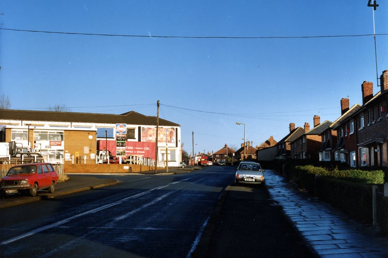 Looking north along Osmondthorpe Lane showing the junction with Ings Road on the left in January 1991. A petrol filling station can be seen beyond this with a removals and storage van parked at the side. The white building behind is Timmerdale's ice cream factory. Semi-detached housing is on the right of the picture and cars are parked by the side of the road.