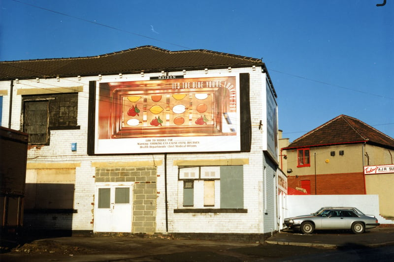 Timmerdale's ice cream manufacturers' equipment factory at the corner of Osmondthorpe Lane and Ings Road. Advertising hoardings adorn the front and side of the building, including an advertisment for cigarettes on the side. Cars are parked at the front of the building. A.J.R. Superstores can be seen on the right. Pictured in January 1991.