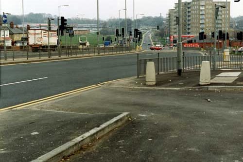 Llooking east along York Road, taken from the lay-by outside the shops.. The junction with Rookwood Avenue is on the right, followed by the Little Chef restaurant and petrol filling station, and behind these blocks of high-rise flats. More housing can be seen on the left. The road is busy with traffic. Pictured in March 1991.