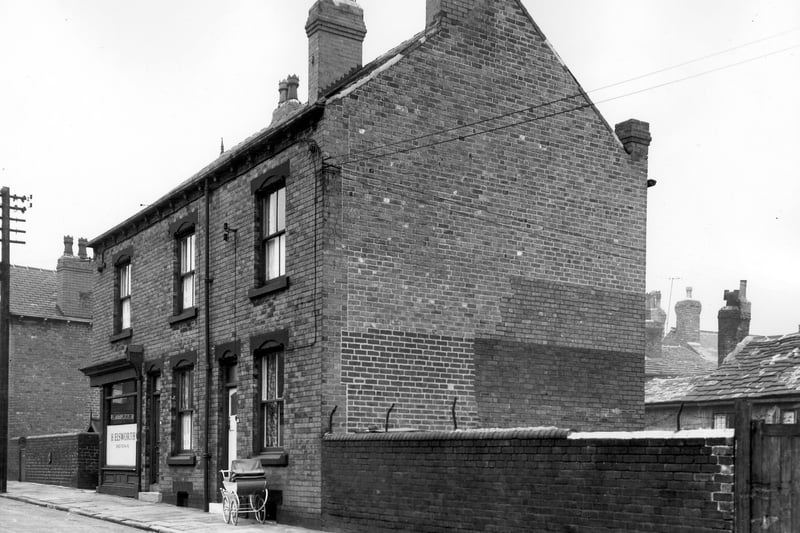 The front and gable end of numbers 16 to 20 Folly Lane. On the far left is a ginnel giving access to Una Mount. At number 20 is H. Elsworth shoe repairs with two terraced houses on the right. On the right is access to the Good Physician Church of England Mission Rooms. Pictured in October 1963.