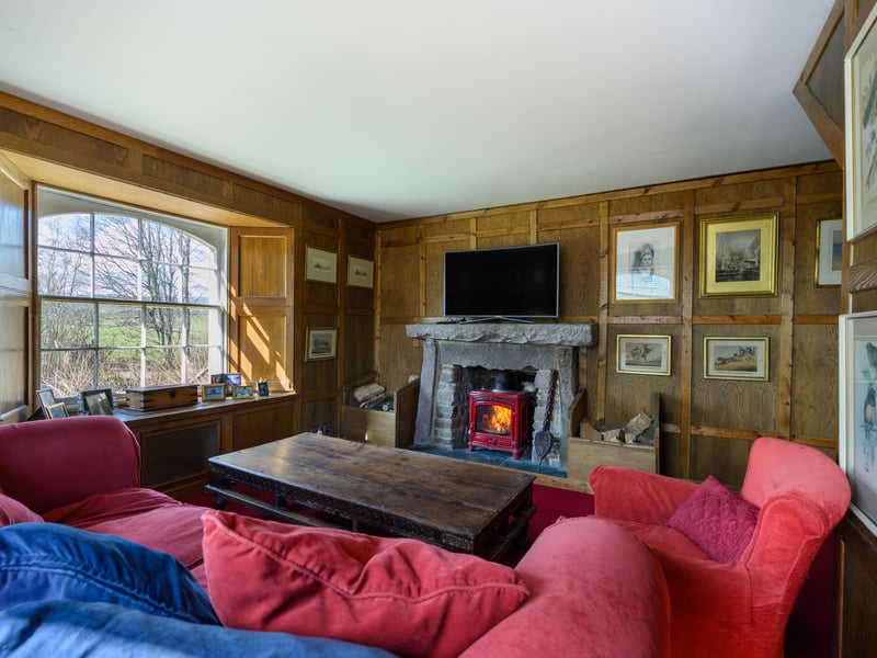 The cosy farmhouse section features an open-plan living, dining, and kitchen space with an Aga range, island, and separate pantry, as well as a timber-clad lounge with wood-burning stove.