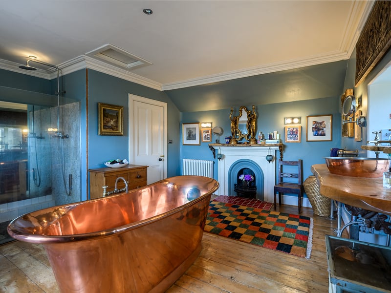 On the first floor of the original house are two double bedrooms and two bathrooms, one of which boasts a free-standing copper bath, a large shower, and original fireplace.