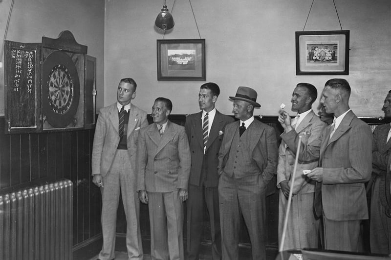 Tottenham Hotspur manager Peter McWilliam (1879 - 1951, centre, in hat), watching some of his players play darts in the recreation room at Spurs' White Hart Lane ground, London, July  26 1938. (Photo by A. Hudson/Topical Press Agency/Hulton Archive/Getty Images)